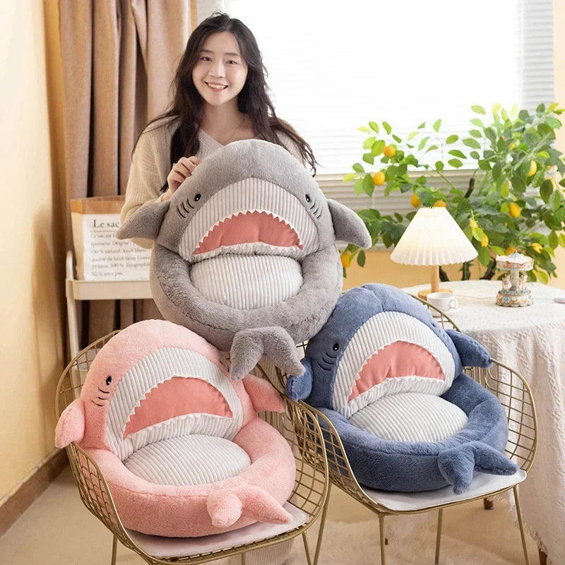 Woman holding a shark-shaped kawaii cushion with two other shark cushions on chairs.