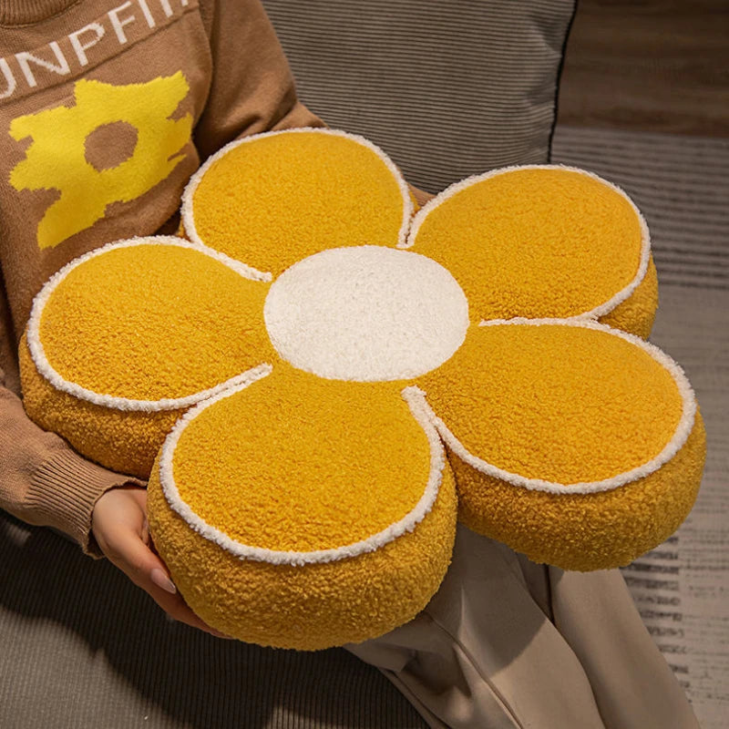 Person holding a yellow flower-shaped kawaii cushion with a white center.
